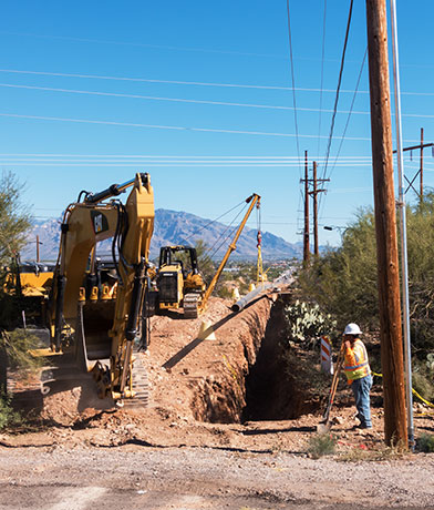 Caterpillar CAT D5K2 pipelayer holding pipe with CAT 316E excavator   Arizona