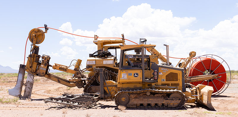 John Deere 450J dozer in front of CAT D8R for scale on Pipe Plow
